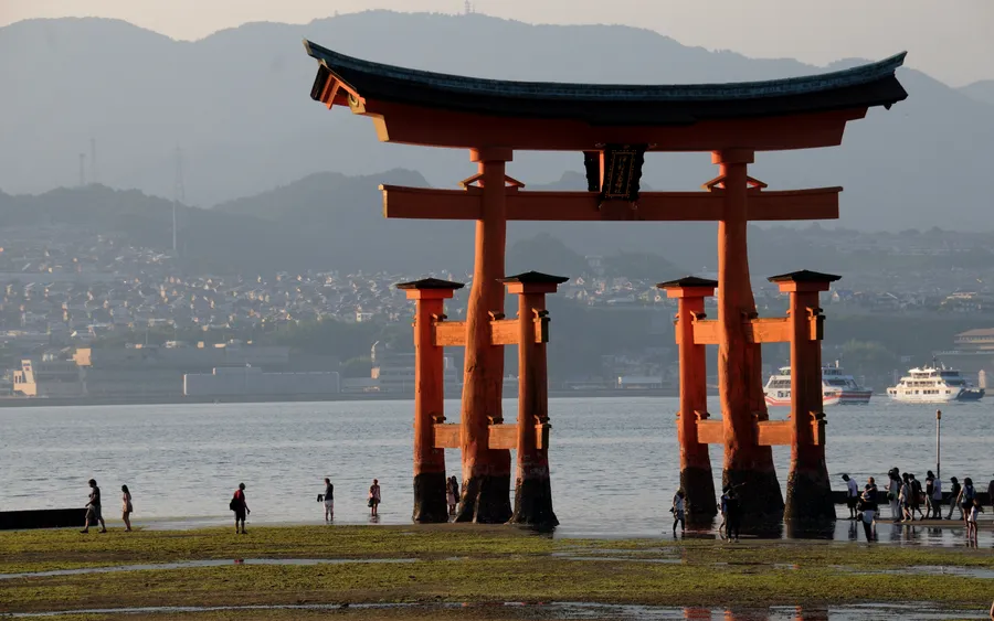 Visitors walking out to the Itsukushima torii gate at low tide, Miyajima