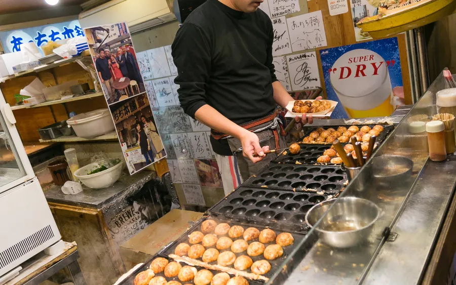 Takoyaki being grilled on a griddle