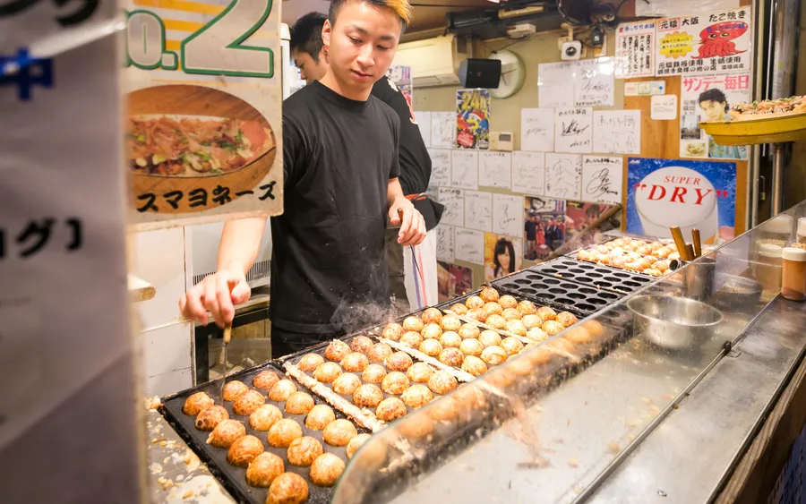 Takoyaki being grilled on a griddle