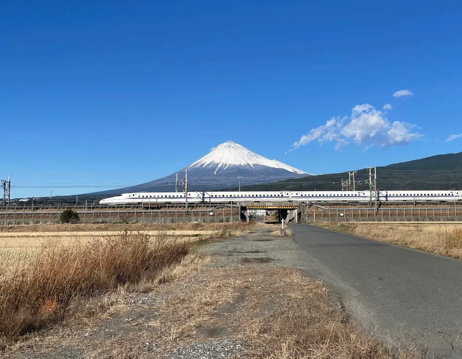 Shinkansen bullet train passing beneath Mount Fuji