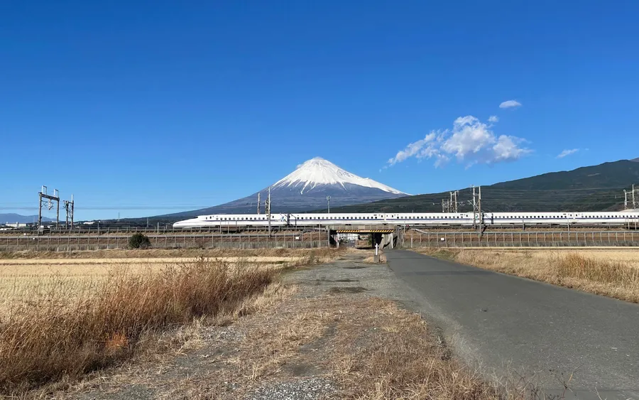 Shinkansen bullet train passing beneath Mount Fuji